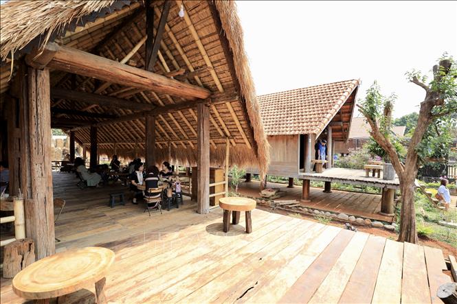 Tourists enjoy coffee in traditional long houses in Ako Dhong village. VNA Photo: Nhật Anh 