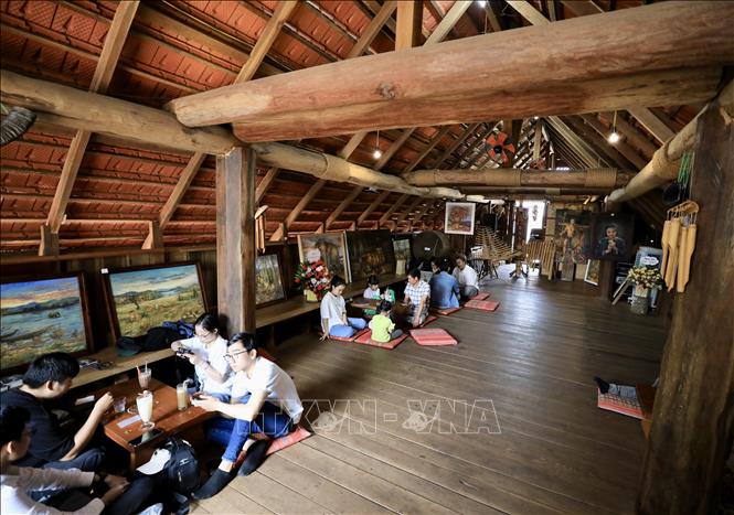 Tourists enjoy coffee in traditional long houses in Ako Dhong village. VNA Photo: Nhật Anh 
