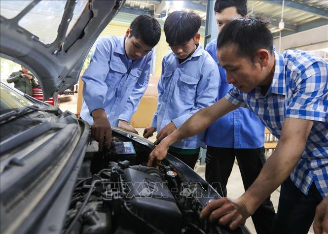 Thầy giáo Hoàng Văn Chuyển (Trường Trung cấp dân tộc nội trú - Giáo dục thường xuyên Bắc Quang) hướng dẫn học sinh lớp Công nghệ ô tô KX - 01 về sửa chữa ô tô. Ảnh: Hoàng Hiếu - TTXVN