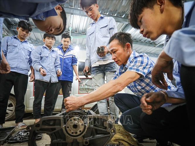Thầy giáo Hoàng Văn Chuyển (Trường Trung cấp dân tộc nội trú - Giáo dục thường xuyên Bắc Quang) hướng dẫn học sinh lớp Công nghệ ô tô KX - 01 thực hành mô đun bảo dưỡng, sửa chữa cơ cấu trục khửu thanh truyền. Ảnh: Hoàng Hiếu - TTXVN