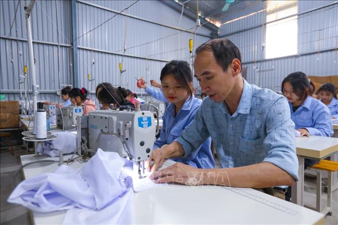 Thầy giáo Đỗ Minh Thắng (Trường Trung cấp dân tộc nội trú - Giáo dục thường xuyên Bắc Quang) hướng dẫn học sinh lớp may thời trang KX - 01 thực hành. Ảnh: Hoàng Hiếu - TTXVN 