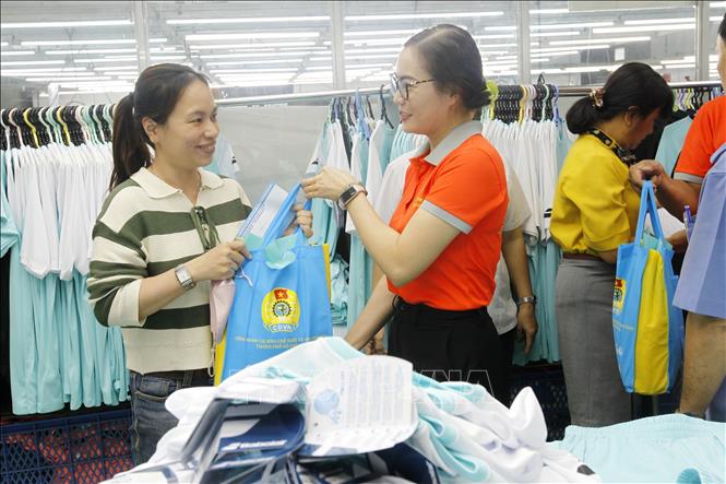 Trong ảnh: Đại diện Công đoàn các khu Chế xuất, Công nghiệp Tp. Hồ Chí Minh trao quà hỗ trợ cho công nhân Công ty TNHH Ampfield (chuyên may hàng thể thao xuất khẩu sang Pháp) bị giảm giờ làm, giảm thu nhập. Ảnh: Thanh Vũ – TTXVN
