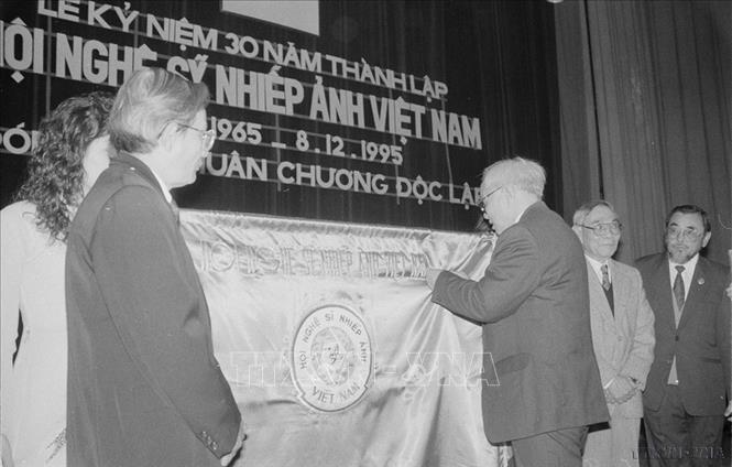 Đồng chí Nguyễn Đức Bình, Bí thư Trung ương Đảng gắn Huân chương Độc lập lên cờ truyền thống của Hội Nghệ sĩ nhiếp ảnh Việt Nam (1995). Ảnh: Đình Trân - TTXVN