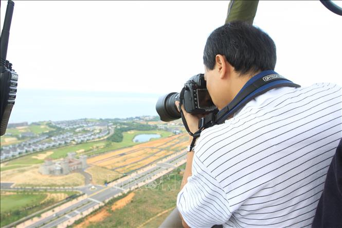 Phóng viên Quang Hải (TTXVN) tác nghiệp từ trên khinh khí cầu tại Lễ hội khinh khí cầu quốc tế Việt Nam lần thứ I - năm 2012 ở Bình Thuận. Ảnh: Nhật Anh - TTXVN
