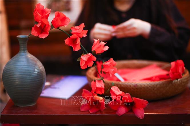 An artisan makes giant bombax ceiba tree's red flowers from paper. VNA Photo: Tuấn Đức