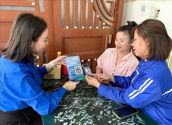 Đoàn viên, thanh niên hướng dẫn hộ kinh doanh cài đặt ứng dụng thanh toán điện tử trên điện thoại thông minh. Ảnh: Nguyễn Nam-TTXVN
