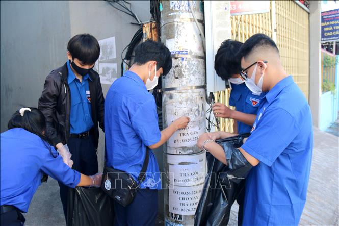 Các bạn đoàn viên thanh niên cạo, gỡ các giấy quảng cáo không đúng quy định trên tuyến đường trung tâm thành phố Phan Thiết. Ảnh: Nguyễn Thanh - TTXVN