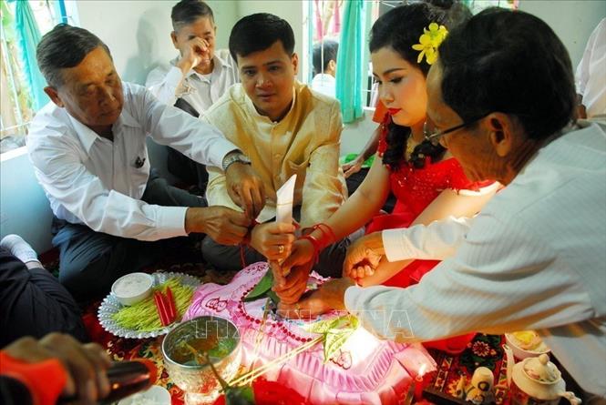 “Lễ cột chỉ tay” cho cô dâu và chú rể tại lễ cưới của người Khmer - nghi thức gắn liền với gia tộc, phong tục tập quán của cộng đồng dân cư Khmer, là lễ chính thức cho phép đôi trai gái thành vợ, thành chồng. Ảnh: Mạnh Linh-