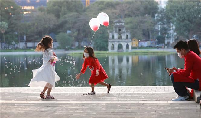 Nhiều gia đình cho con đi chơi tại hồ Gươm trước khoảnh khắc chuyển giao năm mới Tân Sửu 2021. Ảnh: Thanh Tùng - TTXVN