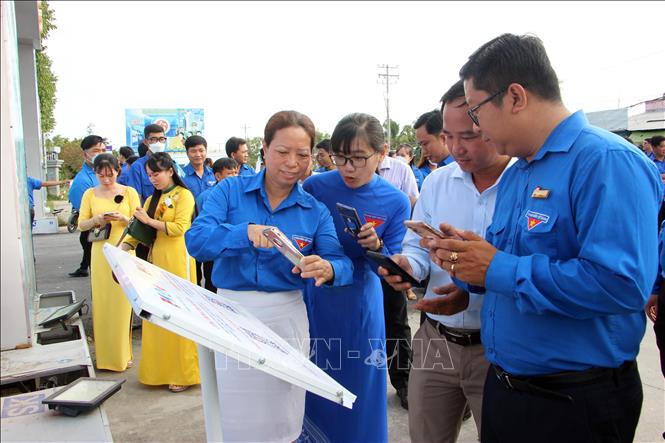 Các đại biểu tham dự trải nghiệm quét mã QR trên bảng công trình trước khu di tích. Ảnh: Trung Kiên - TTXVN