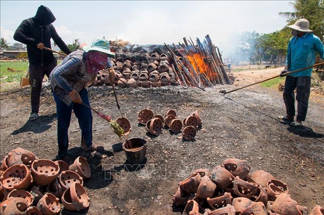 Craftsmen sprinkle a liquid made from leaves and fruits on the newly-burned products' surface to create patterns. VNA Photo: Hồng Đạt