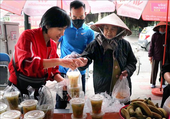 Trong ảnh: Anh chị em tổ cơm từ thiện bán các suất cơm từ thiện tới người có hoàn cảnh khó khăn. Ảnh: Hoàng Ngọc-TTXVN