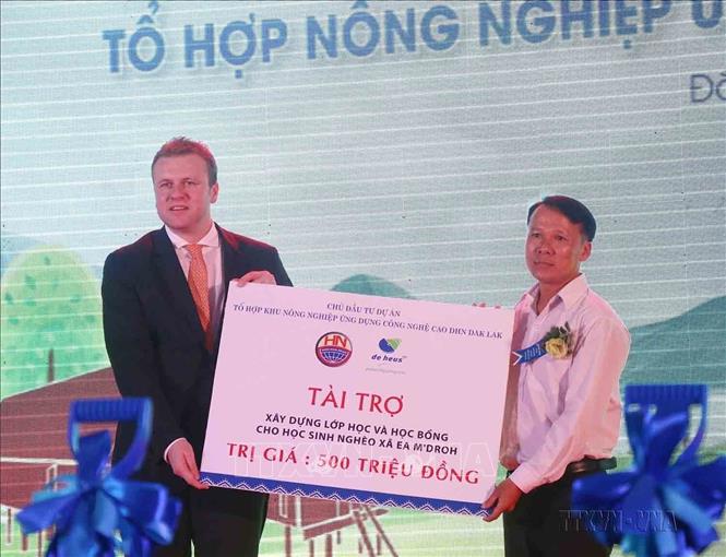Đại diện Tập đoàn De Heus (Hà Lan) - chủ đầu tư Dự án “Tổ hợp Nông nghiệp ứng dụng Công nghệ cao DHN Đắk Lắk” tặng học bổng và tài trợ xây dựng lớp học cho học sinh nghèo xã Ea M’droh, huyện Cư M’gar, tỉnh Đắk Lắk. Ảnh: Tuấn Anh – TTXVN