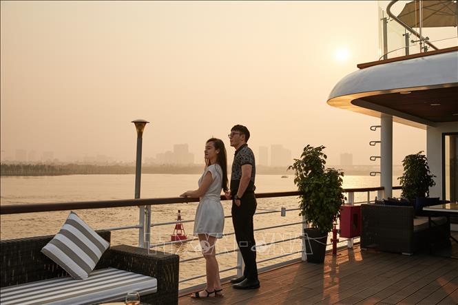 Tourists enjoy the sunset on board of the Jade of River cruise ship during a tour along the Red River in Hanoi. Photo by courtesy/VNA