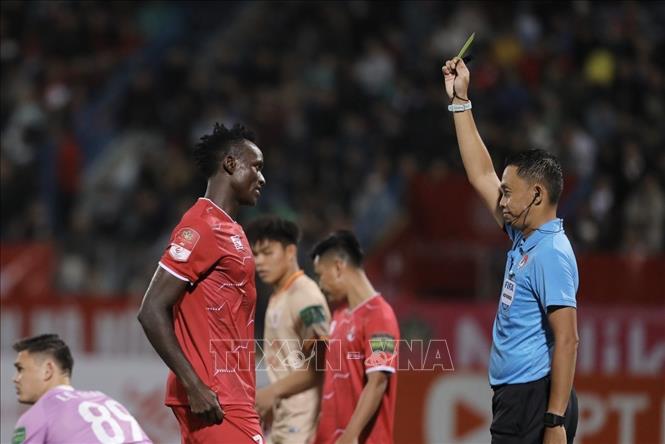 Trọng tài rút thẻ vàng cảnh cáo cầu thủ Joseph (số 7, Hải Phòng) sau tình huống móc bóng nguy hiểm với đội trưởng Tấn Sinh (số 3, CAHN). Ảnh: Minh Quyết - TTXVN