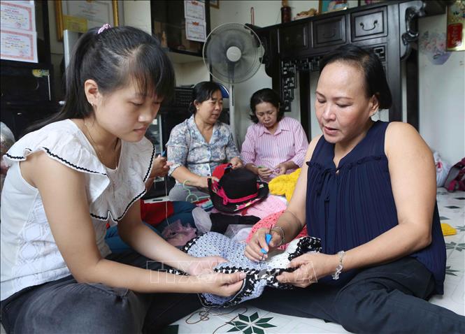 Chị Đinh Thị Tuyết Đào (phải), chủ cơ sở đan len Phước Đào, 174/12 Lê Văn Lương, phường Tân Hưng, Quận 7 (TP. Hồ Chí Minh) là người bị bại liệt từ nhỏ. Năm 2006, chị được Hội Liên hiệp Phụ nữ phường giúp vay vốn xóa đói giảm nghèo, thành lập cơ sở đan móc len thủ công, tạo việc làm cho hơn 40 chị em khu phố có cùng hoàn cảnh. Ảnh: Phương Hoa - TTXVN