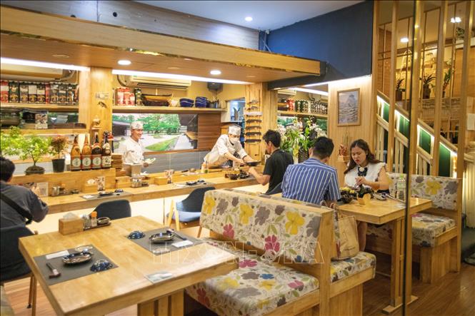 Thực khách Việt Nam và Nhật Bản thưởng thức bữa tối trong không gian bố trí theo phong cách Nhật Bản tại Nhà hàng Vạn Phúc - phố Đào Tấn. Ảnh: Hoàng Hiếu - TTXVN