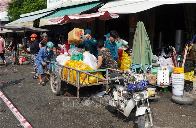 Lực lượng chức năng hỗ trợ người dân mang hàng hóa ra ngoài. Ảnh: Nhựt An - TTXVN