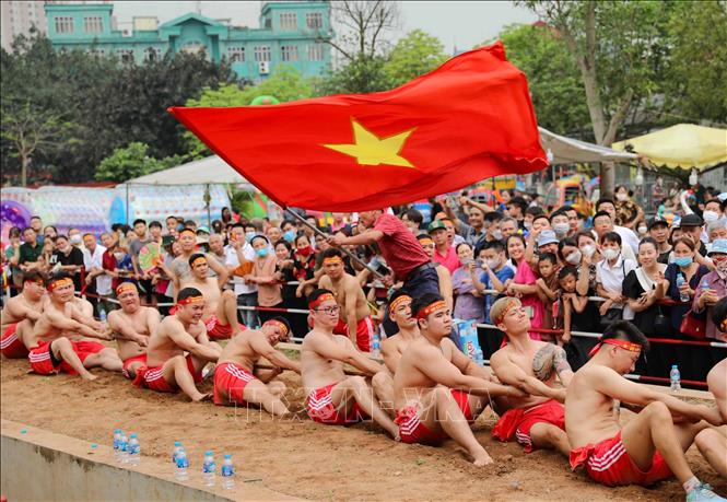 Hàng chục thanh niên ngồi qua một cây song dài từ 50m, đường kính 5cm, mỗi người một tay duỗi thẳng, tay kia co trước ngực, song được kẹp chặt dưới nách của tay co. Ảnh: Thanh Tùng - TTXVN 