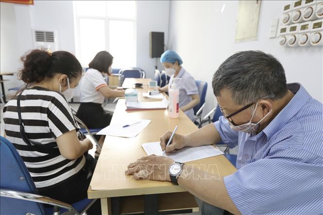 Người dân đến đăng ký tiêm vaccine phòng COVID-19 tại điểm tiêm quận Hai Bà Trưng. Ảnh: Minh Quyết - TTXVN