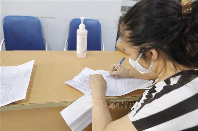 Người dân đến đăng ký tiêm vaccine phòng COVID-19 tại điểm tiêm quận Hai Bà Trưng. Ảnh: Minh Quyết - TTXVN