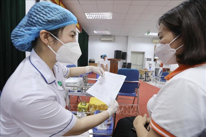 Nhân viên y tế giải thích cho người đến tiêm vaccine COVID-19 tại điểm tiêm Nhà hộ sinh B (quận Hai Bà Trưng). Ảnh: Minh Quyết - TTXVN