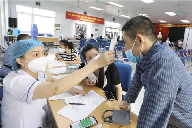 Người dân đến tiêm vaccine được kiểm tra thân nhiệt trước khi tiêm. Ảnh: Minh Quyết - TTXVN