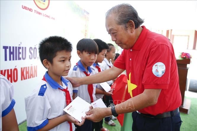 Đồng chí Trương Hòa Bình, nguyên Phó Thủ tướng Chính phủ, trao học bổng cho học sinh có hoàn cảnh khó khăn khu vực biên giới của tỉnh Long An. Ảnh: Đức Hạnh - TTXVN 