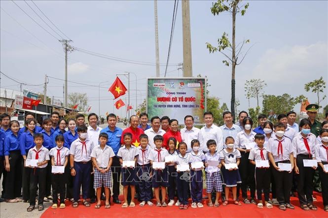 Đại biểu và học sinh chụp hình lưu niệm tại “Đường cờ Tổ quốc” trên địa bàn huyện biên giới Vĩnh Hưng, tỉnh Long An. Ảnh: Đức Hạnh - TTXVN 