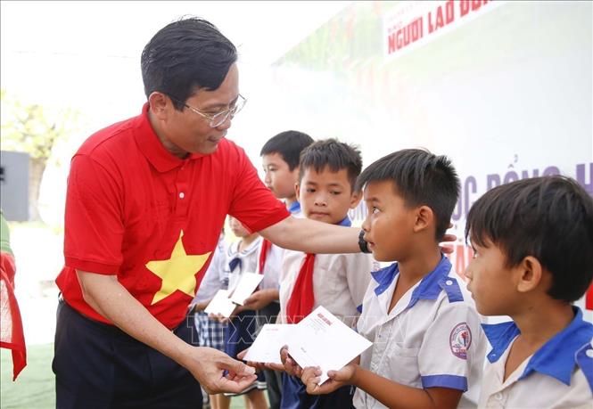 Ông Tô Đình Tuân, Tổng Biên tập Báo Người Lao Động trao học bổng cho học sinh có hoàn cảnh khó khăn khu vực biên giới tỉnh Long An. Ảnh: Đức Hạnh - TTXVN 
