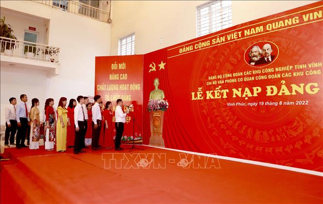 19 đảng viên mới tuyên thệ trước cờ đảng tại Lễ kết nạp đảng viên. Đây là những công nhân lao động trong các khu công nghiệp của tỉnh Vĩnh Phúc. Ảnh: Hoàng Hùng - TTXVN