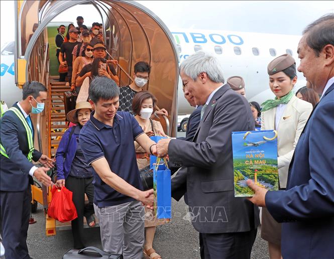 Lãnh đạo Hãng hàng không Bamboo Airways tặng quà cho những vị khách đầu tiên trên chuyến bay thương mại Hà Nội - Cà Mau. Ảnh: Huỳnh Anh - TTXVN