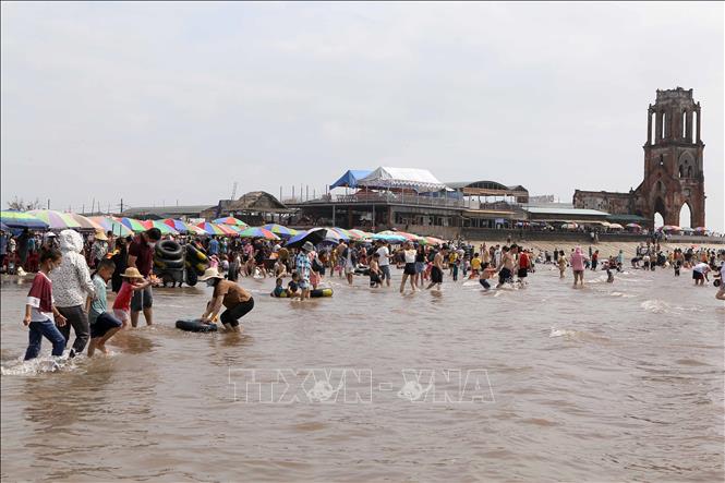 Đông đảo người dân và khách du lịch đến tắm biển tại khu vực nhà thờ đổ Hải Lý. Ảnh: Công Luật - TTXVN
 