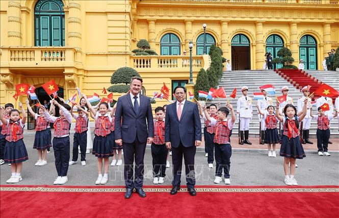 Thủ tướng Phạm Minh Chính và Thủ tướng Đại Công quốc Luxembourg Xavier Bettel với thiếu nhi Thủ đô tại lễ đón. Ảnh: Dương Giang-TTXVN
