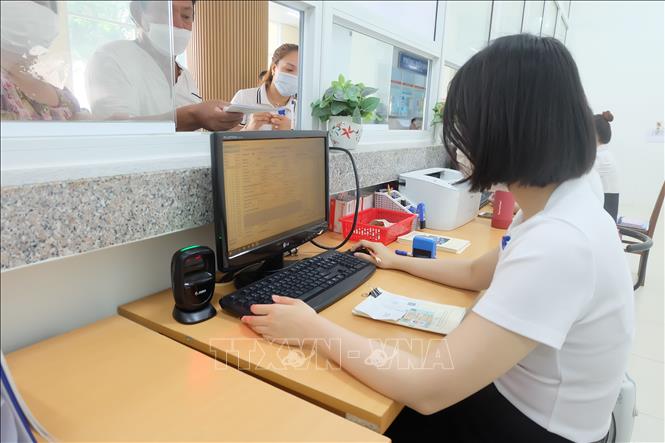 Nhân viên y tế Trung tâm Y tế quận Hải Châu (thành phố Đà Nẵng) quét mã QR trên Căn cước công dân của bệnh nhân để kiểm tra thông tin, và nhập liệu phục vụ khám chữa bệnh Bảo hiểm y tế. Ảnh: Văn Dũng - TTXVN