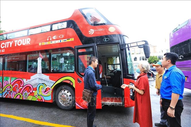 Visitors at the bus stop to join the double-decker bus tour. VNA Photo: Tuấn Anh