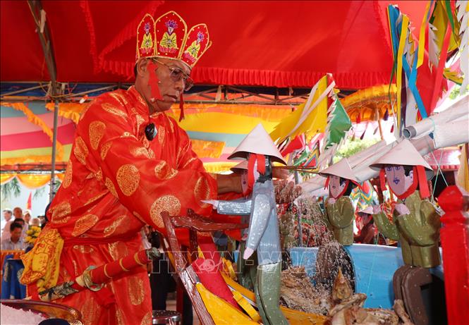 Thực hiện nghi lễ thế lính và rãi gạo, muối ăn cho các hình nhân thế mạng. Ảnh: Phạm Cường-TTXVN