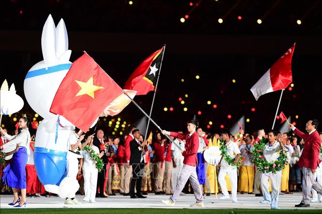 Kình ngư Nguyễn Huy Hoàng giương cao lá Quốc kỳ, dẫn đầu Đoàn thể thao Việt Nam diễu hành trên sân vận động quốc gia Morodok Techo. Ảnh: Hoàng Linh-TTXVN