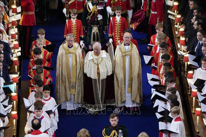 Vua Charles III mặc áo choàng Hoàng gia bước vào Tu viện Westminter ở London, tiến về khu vực hành lễ đăng quang trong tiếng hát của dàn hợp xướng, ngày 6/5/2023. Ảnh: AFP/TTXVN 