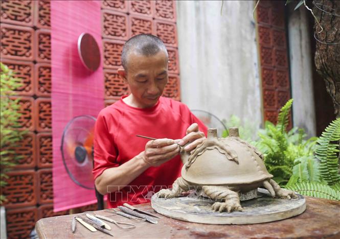 Nghệ nhân Nguyễn Thanh Tuấn (làng nghề Ngũ Xã) tỉ mỉ với công đoạn tạo mẫu. Ảnh: Tuấn Đức - TTXVN