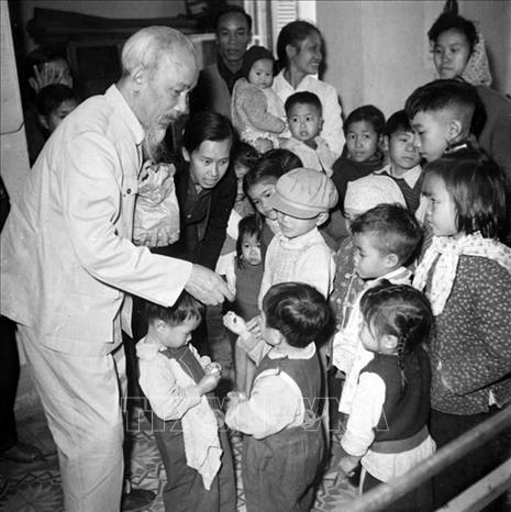 Bác Hồ chia kẹo cho các cháu thiếu nhi ở nhà trẻ của con em công nhân nhà máy cao su Sao Vàng, xà phòng Hà Nội và thuốc lá Thăng Long (Khu Cao-Xà-Lá), ngày 15/2/1961. Ảnh: Tư liệu TTXVN