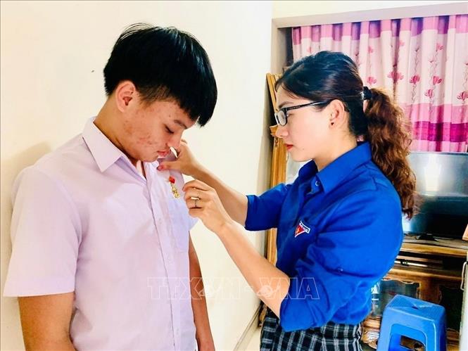 Phó Bí thư Tỉnh đoàn Thanh Hóa Phùng Tố Linh trao Huy hiệu Tuổi trẻ dũng cảm cho em Phạm Ngọc Hoàng Long, lớp 11A1, trường THPT Yên Định 3, huyện Yên Định vì đã có hành động dũng cảm cứu người bị đuối nước. Ảnh: Hoa Mai - TTXVN