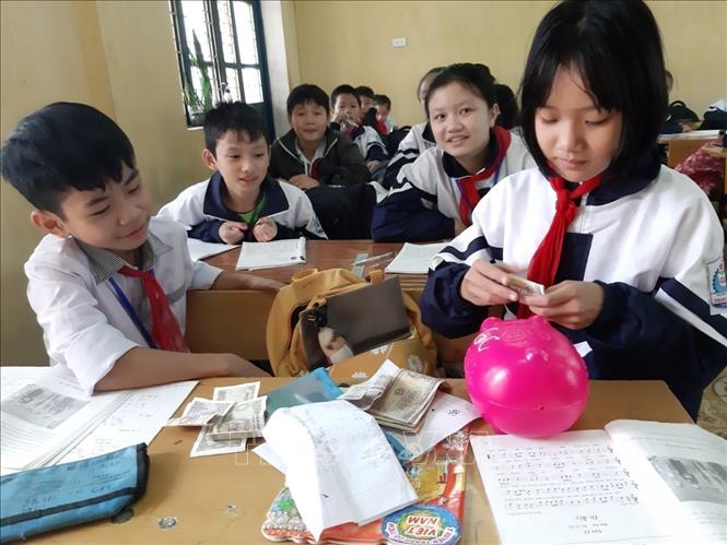 Học sinh trường Tiểu học Bắc Hồng ở thị xã Hồng Lĩnh (Hà Tĩnh) tiết kiệm mỗi ngày 1.000 đồng đến 2.000 đồng từ tiền tiêu vặt để bỏ vào heo nhựa giúp đỡ các bạn nghèo. Ảnh: TTXVN phát