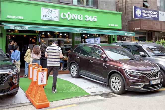 Trong ảnh: Bất kể nắng mưa, thực khách Hàn Quốc vẫn kiên nhẫn xếp hàng đứng chờ để được thưởng thức các món ăn truyền thống Việt Nam. Ảnh: Anh Nguyên-PV TTXVN tại Hàn Quốc.