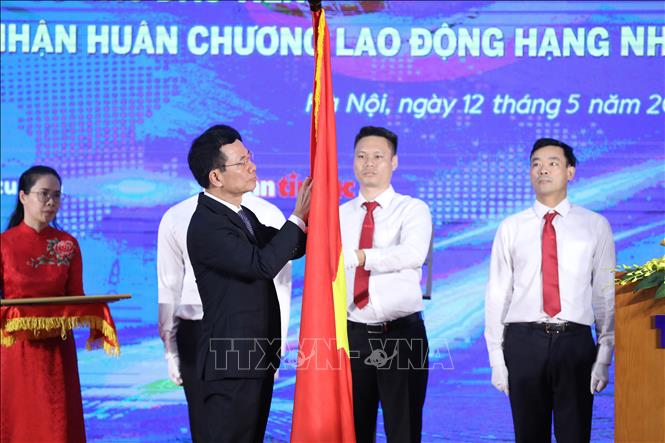 Trong ảnh: Bộ trưởng Bộ Thông tin và Truyền thông Nguyễn Mạnh Hùng gắn Huân chương Lao động hạng Nhất lên lá cờ truyền thống của Báo Tin tức. Ảnh: Minh Đức - TTXVN