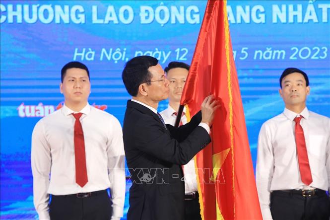 Bộ trưởng Bộ Thông tin và Truyền thông Nguyễn Mạnh Hùng gắn Huân chương Lao động hạng Nhất lên lá cờ truyền thống của Báo Tin tức. Ảnh: Tuấn Anh - TTXVN