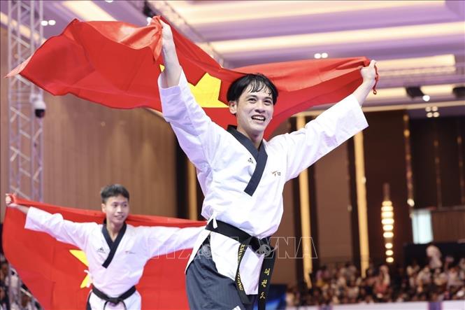 Niềm vui của 3 VĐV Phạm Quốc Việt, Nguyễn Thiên Phụng, Nguyễn Trọng Phúc sau khi giành HCV nội dung Quyền tiêu chuẩn đồng đội nam với thành tích 7,54 điểm. Ảnh: Minh Quyết - TTXVN