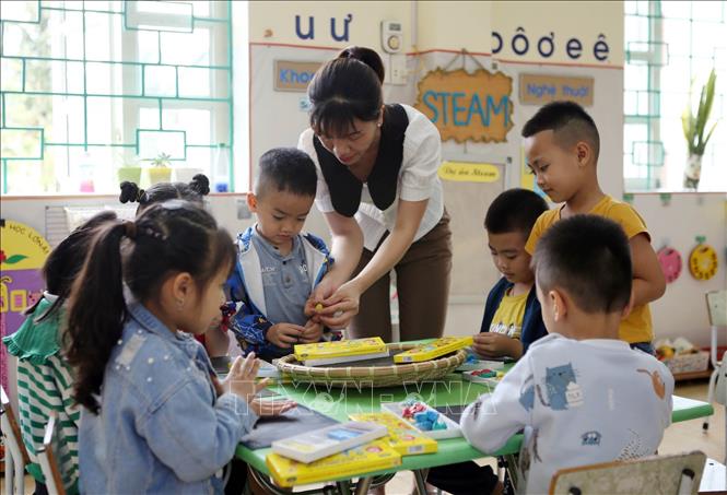 Trong ảnh: Giáo viên Trường Mầm non thị trấn Than Uyên, trường đạt chuẩn quốc gia mức độ I, đang trong lộ trình lên chuẩn mức II hướng dẫn học sinh lớp 5 tuổi cách tạo hình. Ảnh: Quý Trung – TTXVN