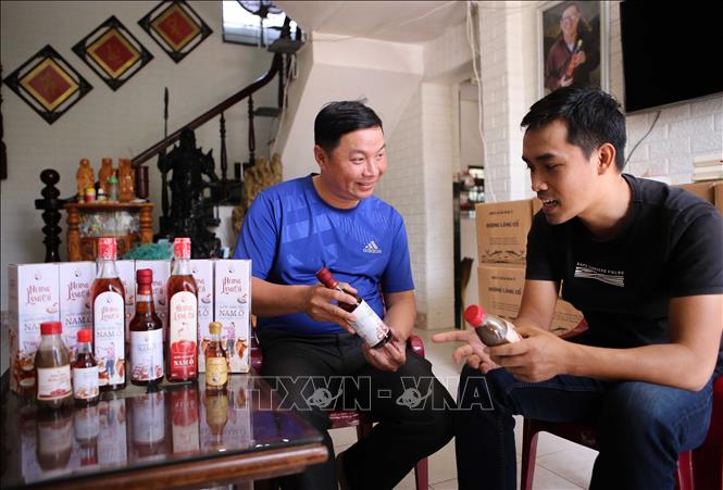 ‘Huong Lang Co’ (Ancient Village Savour) fish sauce’s owner Bui Thanh Phu (L) introduces his products to a visitor. VNA Photo: Trần Lê Lâm