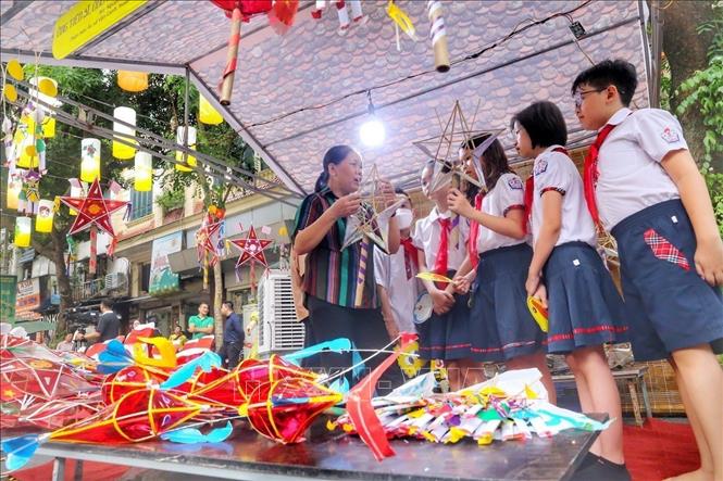 Nghệ nhân Nguyễn Thị Tuyến chia sẻ cách làm đèn ông sao cho học sinh nhân dịp Tết Trung thu truyền thống 2022. Ảnh: Tuấn Đức - TTXVN
